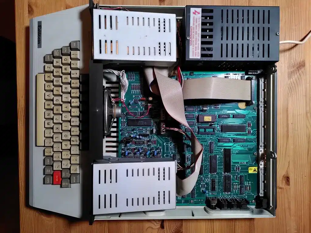 Inside a Tatung Einstein: the keyboard, floppy drive bays and green motherboard exposed.