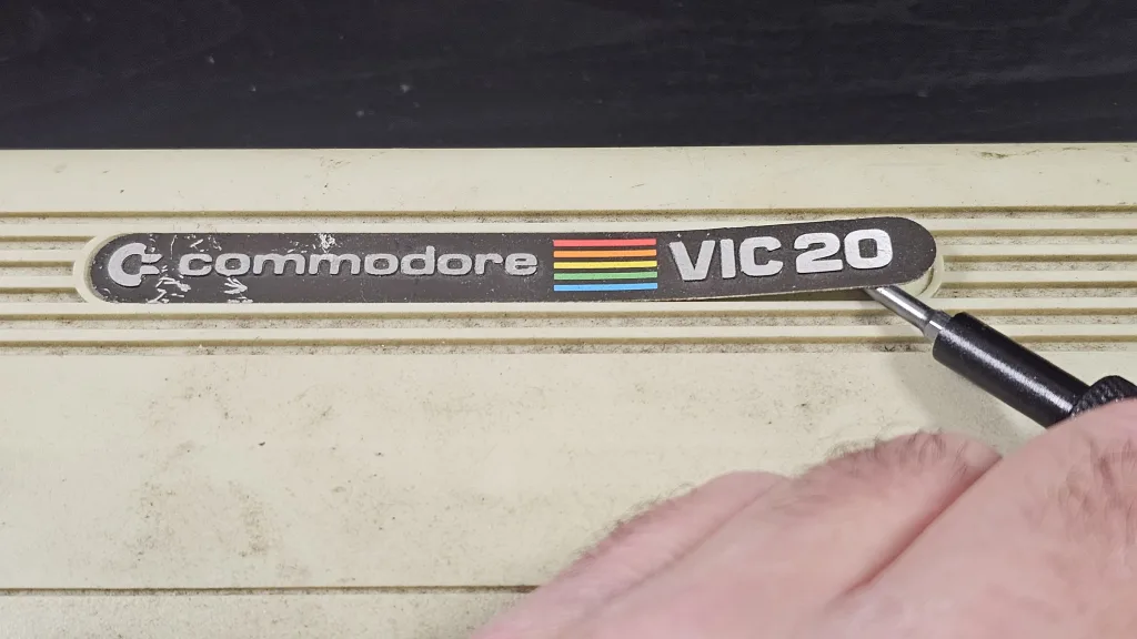 Lifting the VIC-20 badge with a screwdriver. Next time it will be a plastic tool