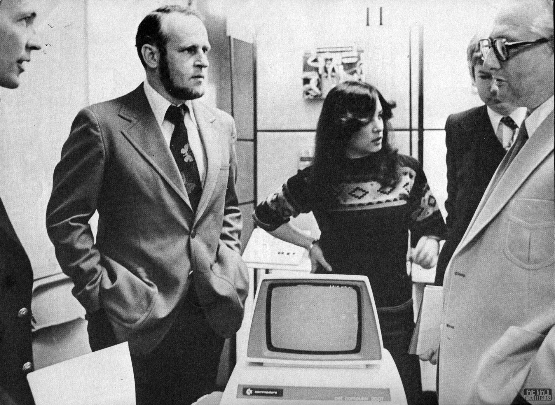 Black-and-white photograph of people standing around a Commodore PET 2001 at a trade show